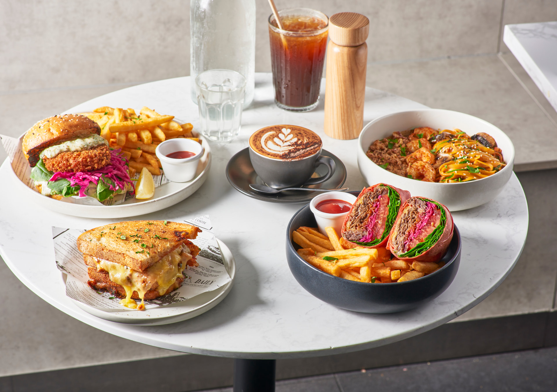 Burger, toastie, bulgogi wrap and coffee on a marble table